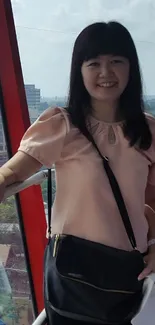 Woman in a pink blouse smiling in front of a scenic view.