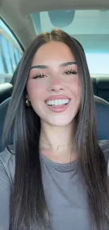 Smiling woman with long hair in a car, exuding elegance.