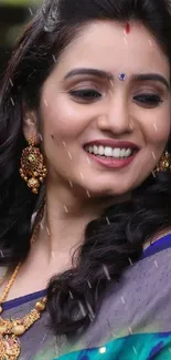 Smiling woman in colorful saree with elegant jewelry.