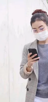 Woman with mask checking smartphone on the street.