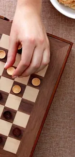 Hand playing a wooden board game on an elegant setup.