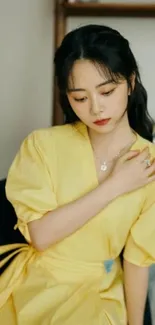 Woman in elegant yellow dress sitting calmly.