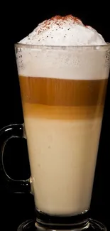 Elegant latte art with creamy layers in a glass against a black background.