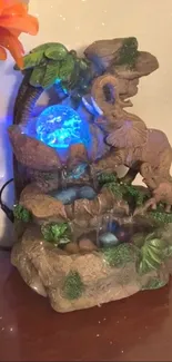 Glowing elephant waterfall sculpture art with blue light and nature elements.