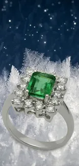 Emerald and diamond ring on frosty background with deep blue hues.