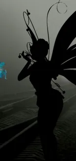 Silhouette of a fairy on railway tracks with a foggy night backdrop.