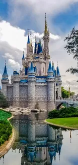 Enchanting castle reflected in tranquil water with lush greenery and blue sky.