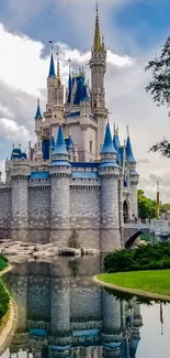 Majestic castle with blue turrets reflected in a tranquil moat under a dynamic sky.