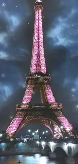 Eiffel Tower at night with pink lights and cloudy sky.