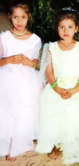 Two young girls in elegant evening dresses outdoors.