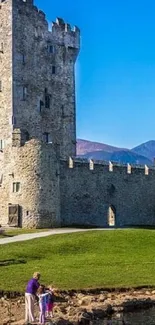 Scenic view of Irish castle with mountains and blue sky.