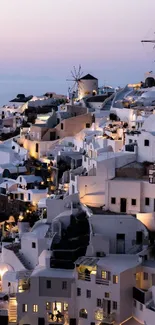 Santorini's white buildings at sunset with windmills and a pink sky.