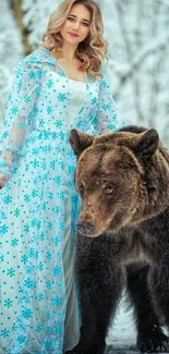 Woman in blue dress standing with bear in snow-covered forest.