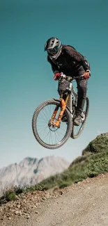 Cyclist jumps on a mountain bike against a sky-blue background.