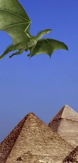 Green dragon flying over the pyramids against a bright blue sky.