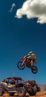 Biker jumps over buggy in desert landscape under blue sky.