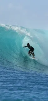 Surfer rides a powerful turquoise wave with clear skies.