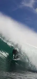 Surfer catching a giant wave under a clear blue sky.