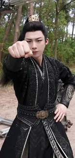 Martial artist in traditional black attire in forest setting.