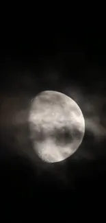 Moon partially veiled by clouds in dark sky, creating an ethereal look.