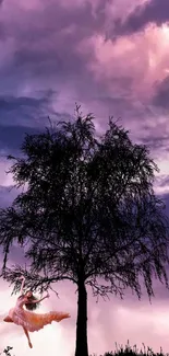 A tree silhouette against a vibrant purple sky with a dancer below.