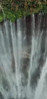 Aerial view of a majestic waterfall amidst lush green forest.