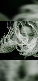 Windblown hair against a dark backdrop in monochrome style.