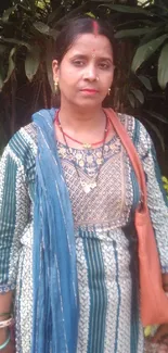 Woman in ethnic attire with green foliage background.