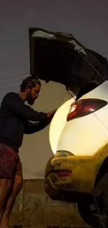 Man standing by a car trunk in the evening.