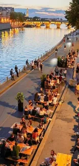 Evening crowd gathered by a lit riverbank.