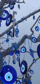 Tree adorned with blue evil eye charms against a calm sky.