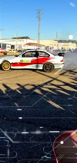 Action-packed car drift scene with shadows on a racetrack during the day.