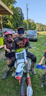 Young bikers on dirt bikes with helmets in a grassy outdoor area.