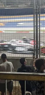 Formula 1 race car speeding on track with spectators watching closely.