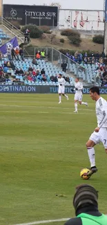 Live soccer match on green field with players in action.