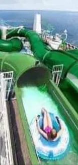 Person enjoying green waterslide with ocean view.