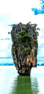 Tropical island with rock formation and lush greenery against blue skies.