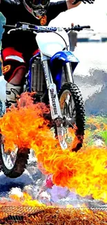 Motorbike jump over fiery blaze in extreme sports wallpaper.