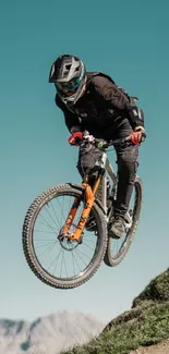 Cyclist performing a jump on a mountain trail with scenic backdrop.