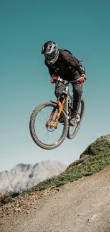 Cyclist mid-air during mountain bike ride on rugged trail.