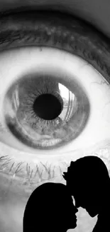 Close-up eye with couple's silhouette in grayscale.