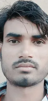 Close-up portrait of a young man with dark hair and serious expression.