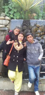 Family posing in front of a waterfall at a scenic park.