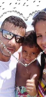 Family of three smiling within a heart-shaped frame at the beach.