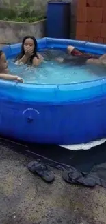 Family enjoying in a blue inflatable pool outdoors.