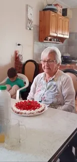 Elderly woman at family gathering with cake in a cozy kitchen.