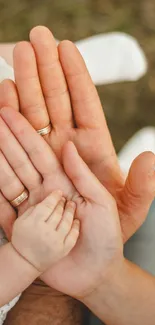 Close-up of baby hand held by two adult hands, symbolizing family unity.