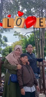 Family standing outdoors with love sign.