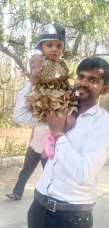 Father holding child outdoors in sunlit nature.