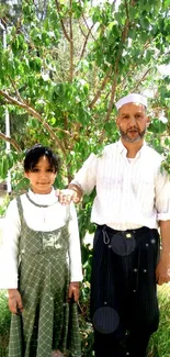 Father and daughter standing under a leafy tree on a sunny day.